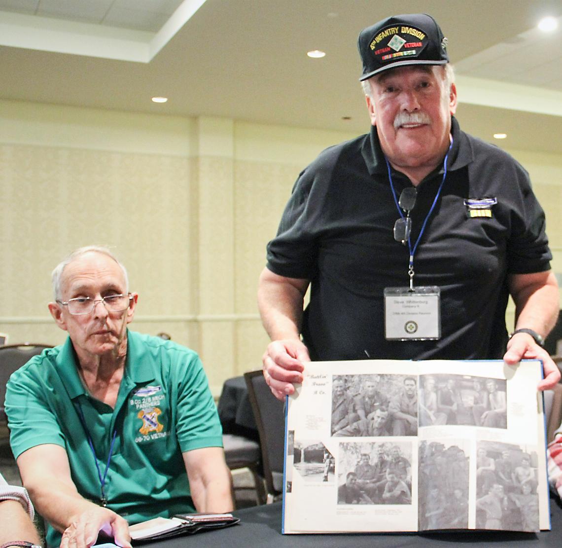 Steve Wittenberg, right, shows off the 1968 military yearbook that helped him track down fellow members of B Company, including George Hosso of Chicago, left.
