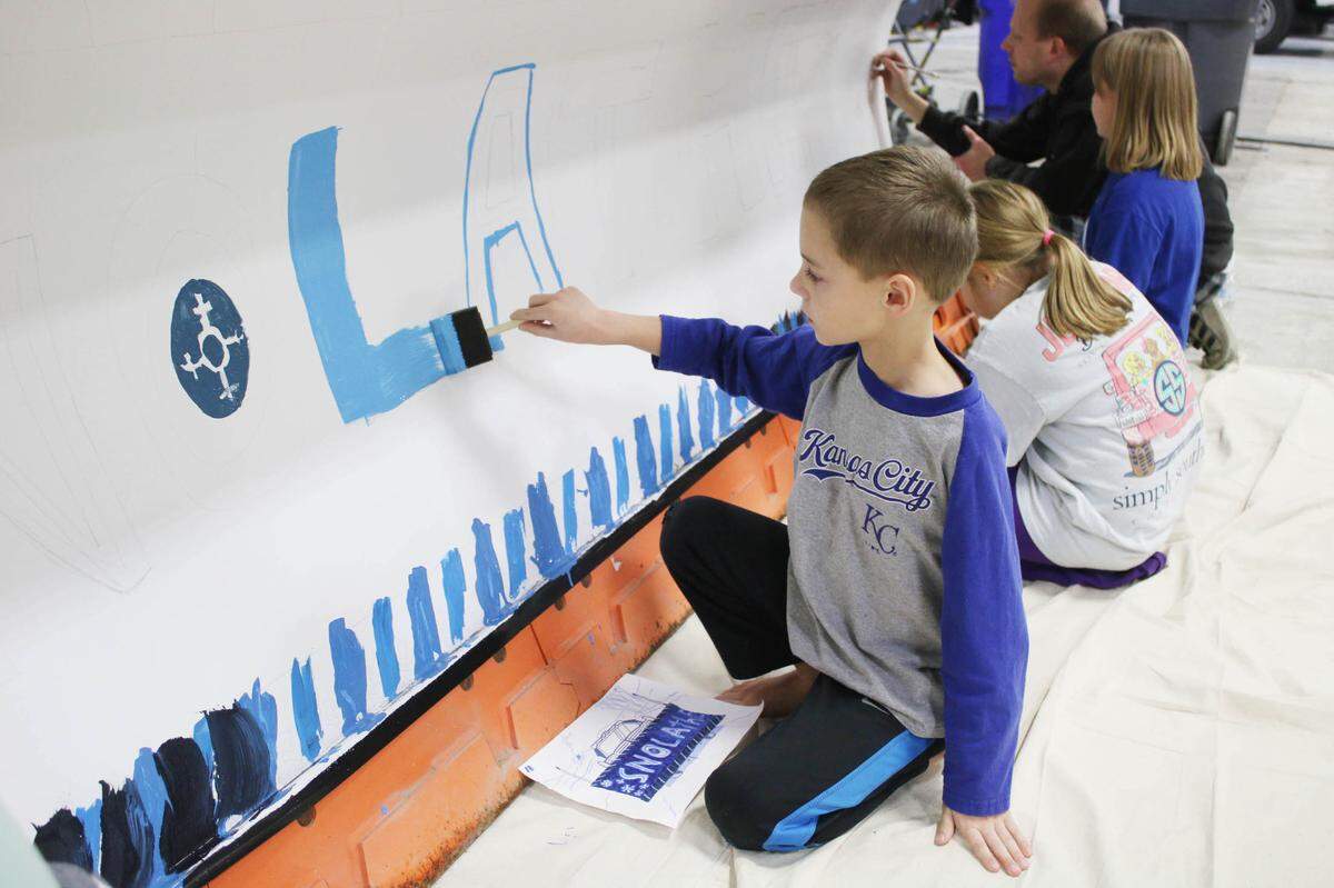 Christopher Childs, 8, helps paint his sister Katie Childs’ design on a snow plow as part of the snOlathe art contest.