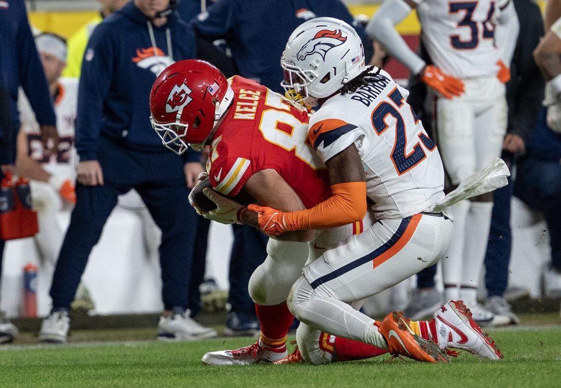 Kansas City Chiefs tight end Travis Kelce (87) is tackled by Denver Broncos cornerback Jahdae Barron (23) during the second half at GEHA Field at Arrowhead Stadium on Thursday, Dec. 25, 2025, in Kansas City.  Denver defeated the Chiefs, 20-13. 
