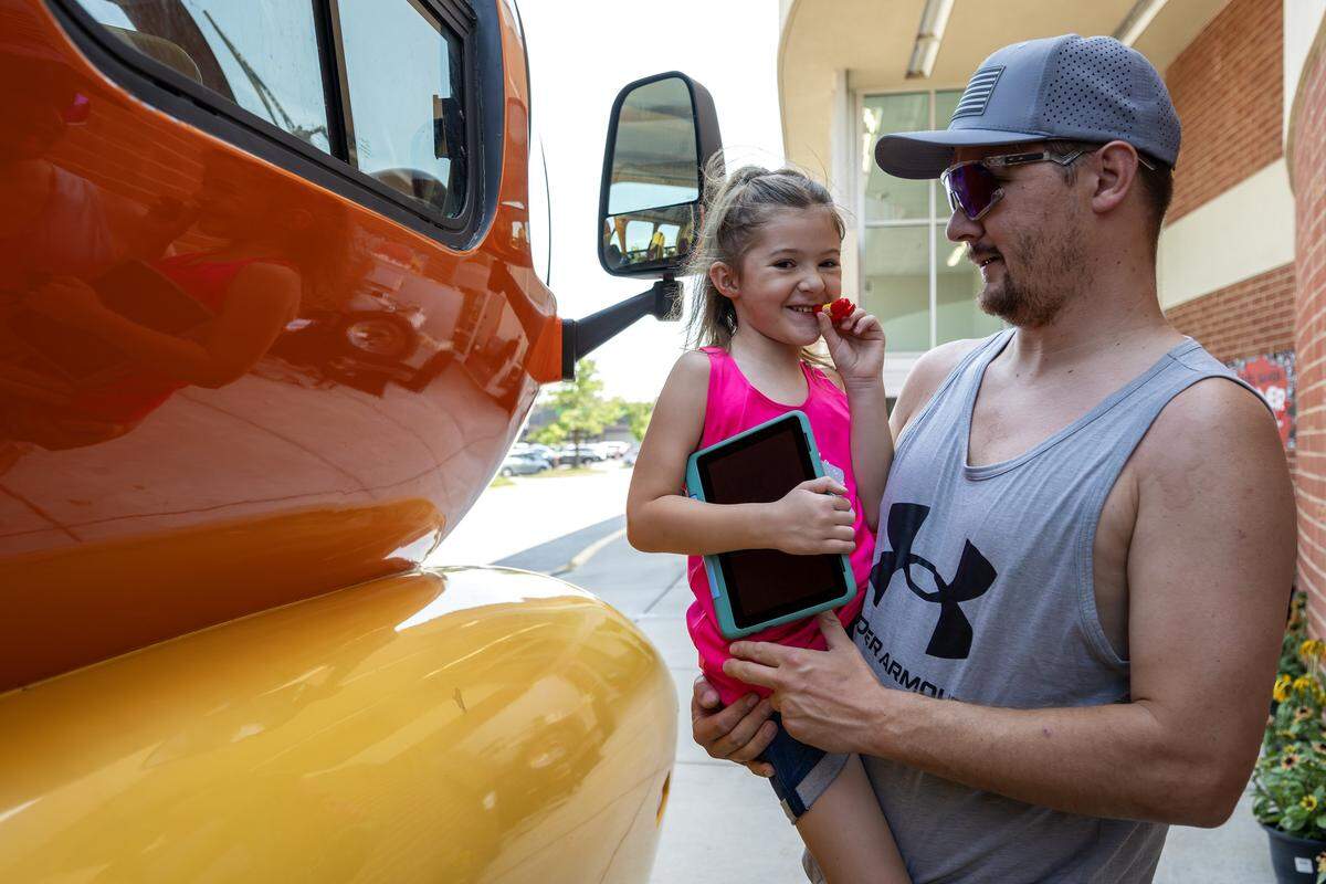 Dakota Tucker holds his 5-year-old daughter, Scarlett, who smiles as she holds an Oscar Mayer whistle given to her during a visit to the Wienermobile.