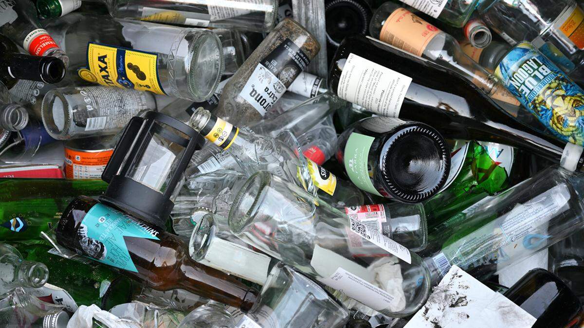 Chania, Crete - August 07, 2022: Trash can full of used glass bottles. Environment pollution with glass waste. Recycling glass. litter littering garbage