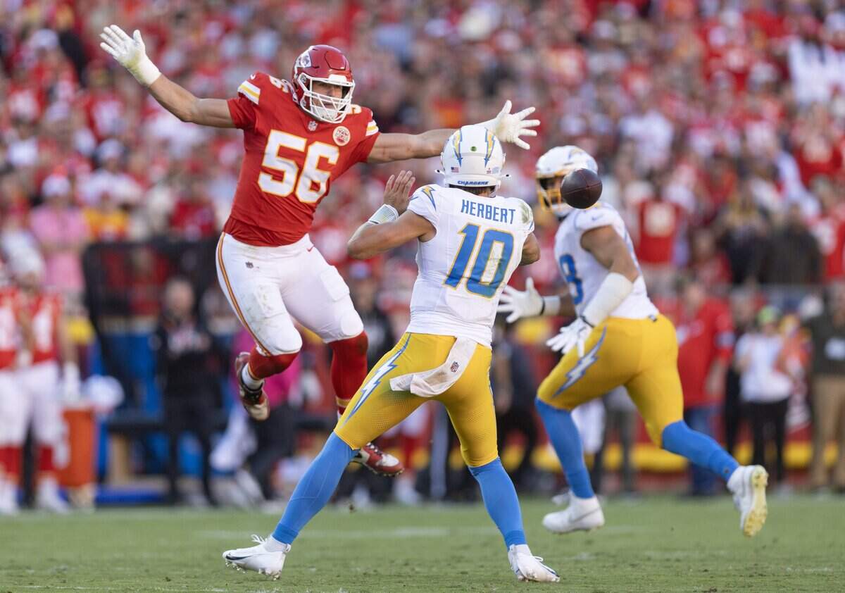 Kansas City Chiefs defensive end George Karlaftis (56) pressures Los Angeles Chargers quarterback Justin Herbert (10) during the first half on Sunday at Arrowhead Stadium.