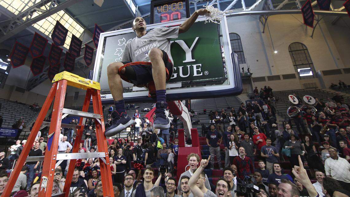 Penn's Darnell Foreman sits in the basket and waves the net after the Quakers' Ivy League championship game victory over Harvard on Sunday.