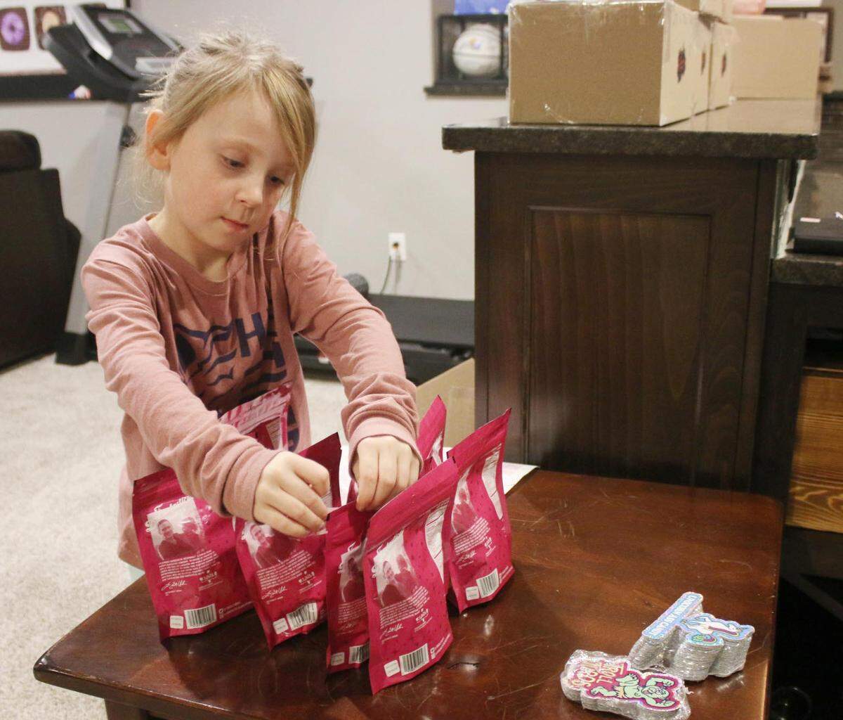 Charlotte Urban puts stickers on packages of Troll Turds candy as part of business she has with her dad called Fantastical Droppings.