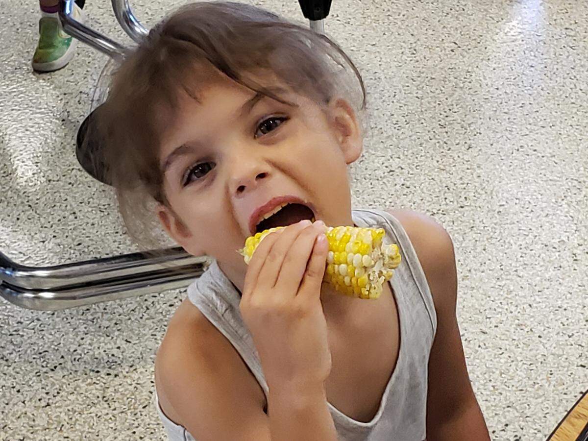 Lyra Crane enjoys an ear of corn at Pleasant Lea Elementary.