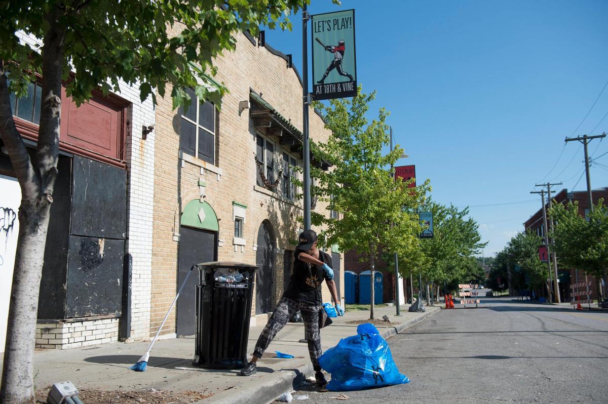 Jacqueline Williams of Kansas City wiped sweat from her face as she volunteered to clean up along Vine Street in the historic district Sunday after a Juneteenth celebration the previous evening.