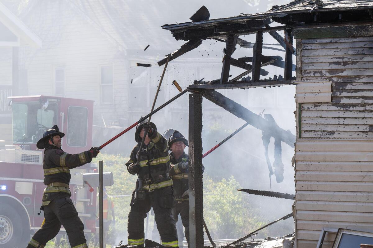 Kansas City firefighters use a fireman’s hooks to break apart potential embers from a house fire near the intersection of Norton Avenue and East 26th Street in Kansas City on Tuesday, April 15, 2025.