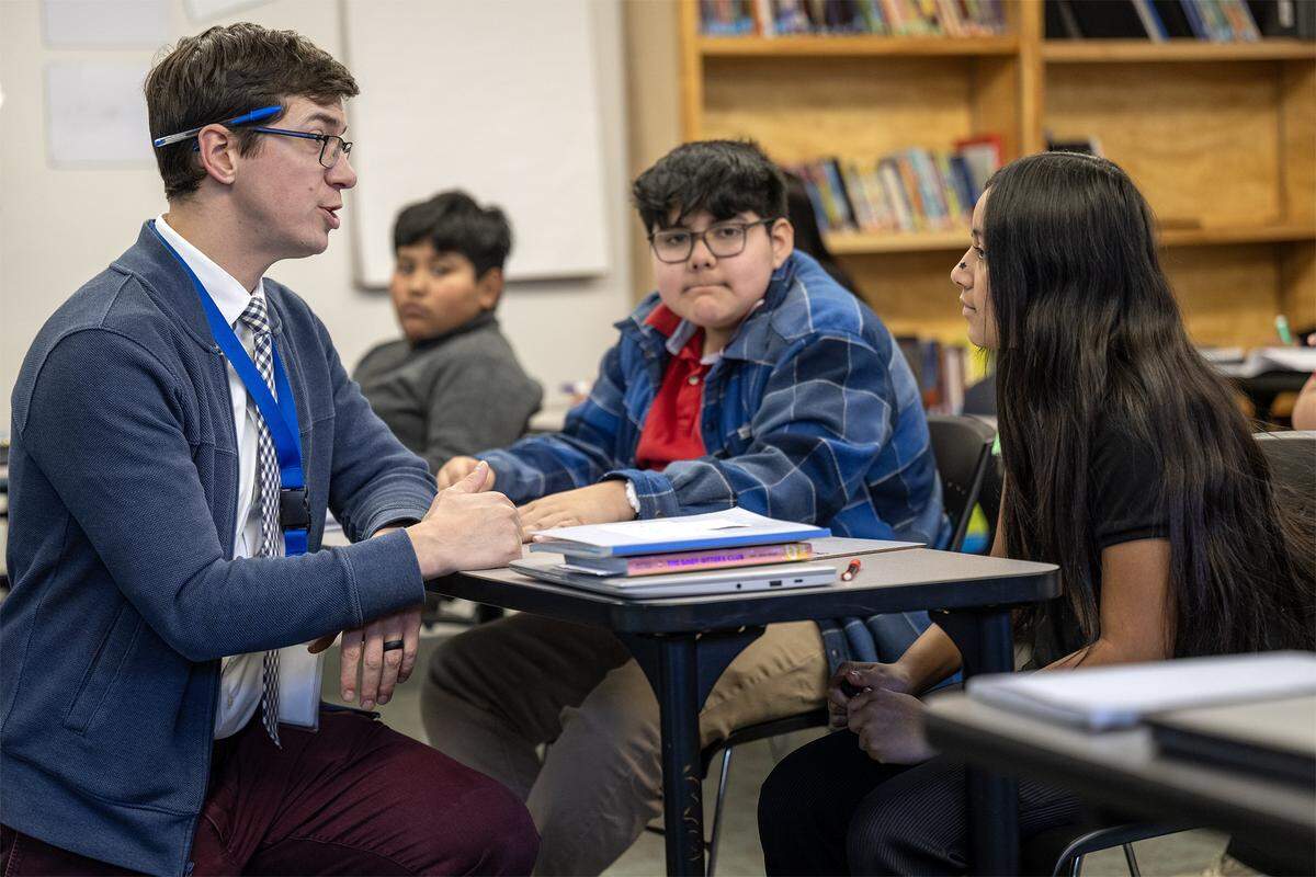 Christopher Leavens, an English language development teacher at Guadalupe Centers Middle School, talks with Nancy, a seventh grade student during class on Thursday, Dec. 4, 2025, in Kansas City. Since the school, a Kansas City charter school, has no library, Leavens has started a small library in his classroom and is on a quest to get more books for the students.