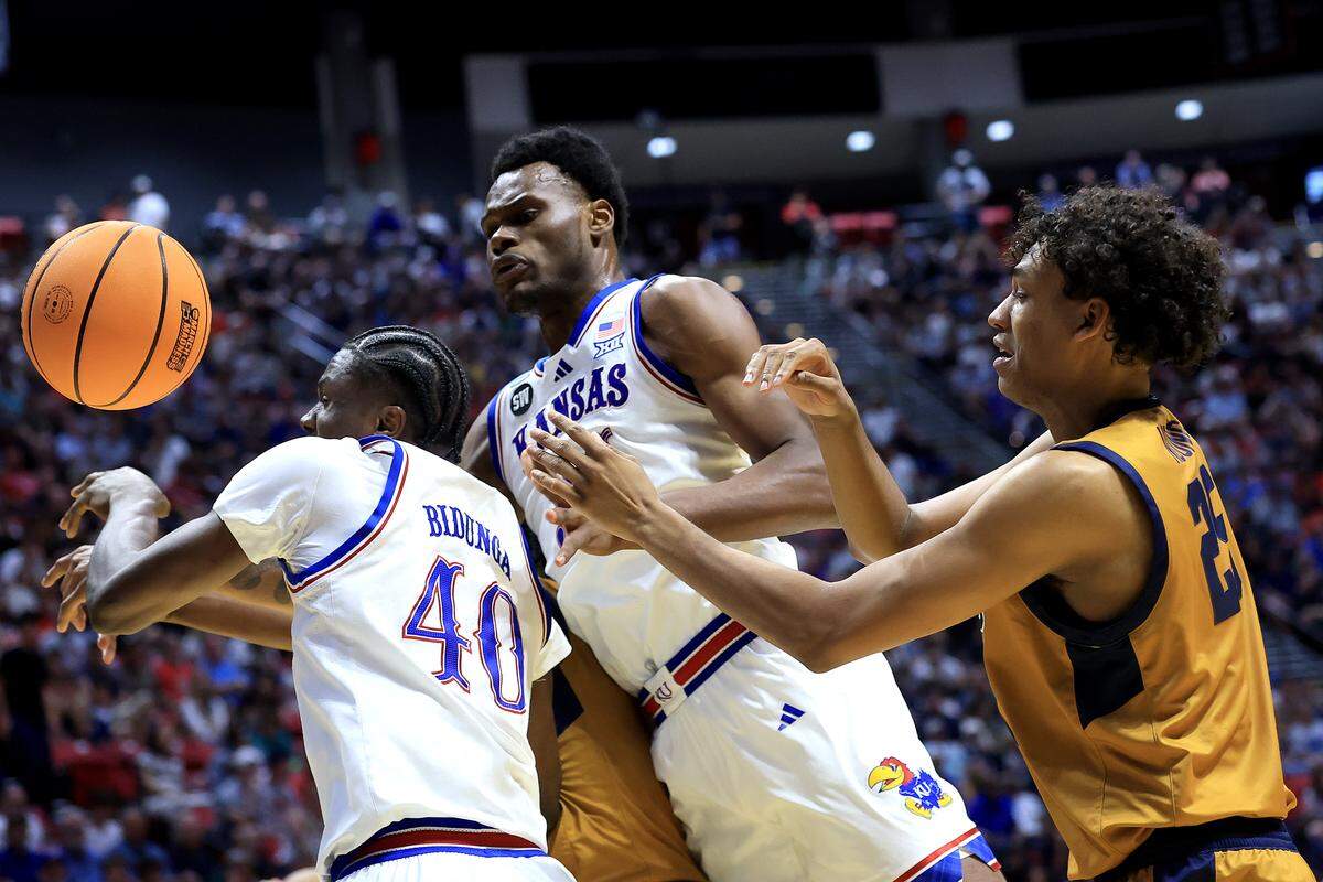 Thomas Ndong #25 of the California Baptist Lancers battles for possession against Flory Bidunga #40 and Paul Mbiya #34 of the Kansas Jayhawks at Viejas Arena in San Diego.