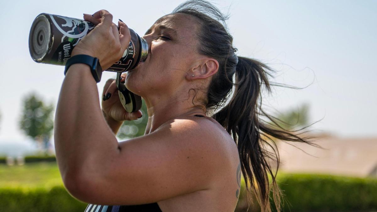 Brianna Walters takes a water break while exercising during a hot day at the National WWI Museum and Memorial on Wednesday, June 28, 2023, in Kansas City.