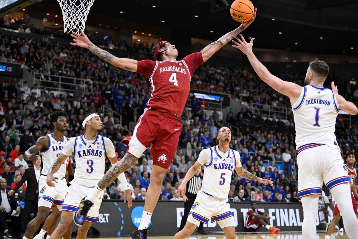 Arkansas Razorbacks forward Trevon Brazile (No. 4) reaches to keep the ball away from Kansas Jayhawks center Hunter Dickinson during an NCAA Tournament men’s basketball game at Amica Mutual Pavilion in Providence, Rhode Island, on Thursday, March 20, 2025.