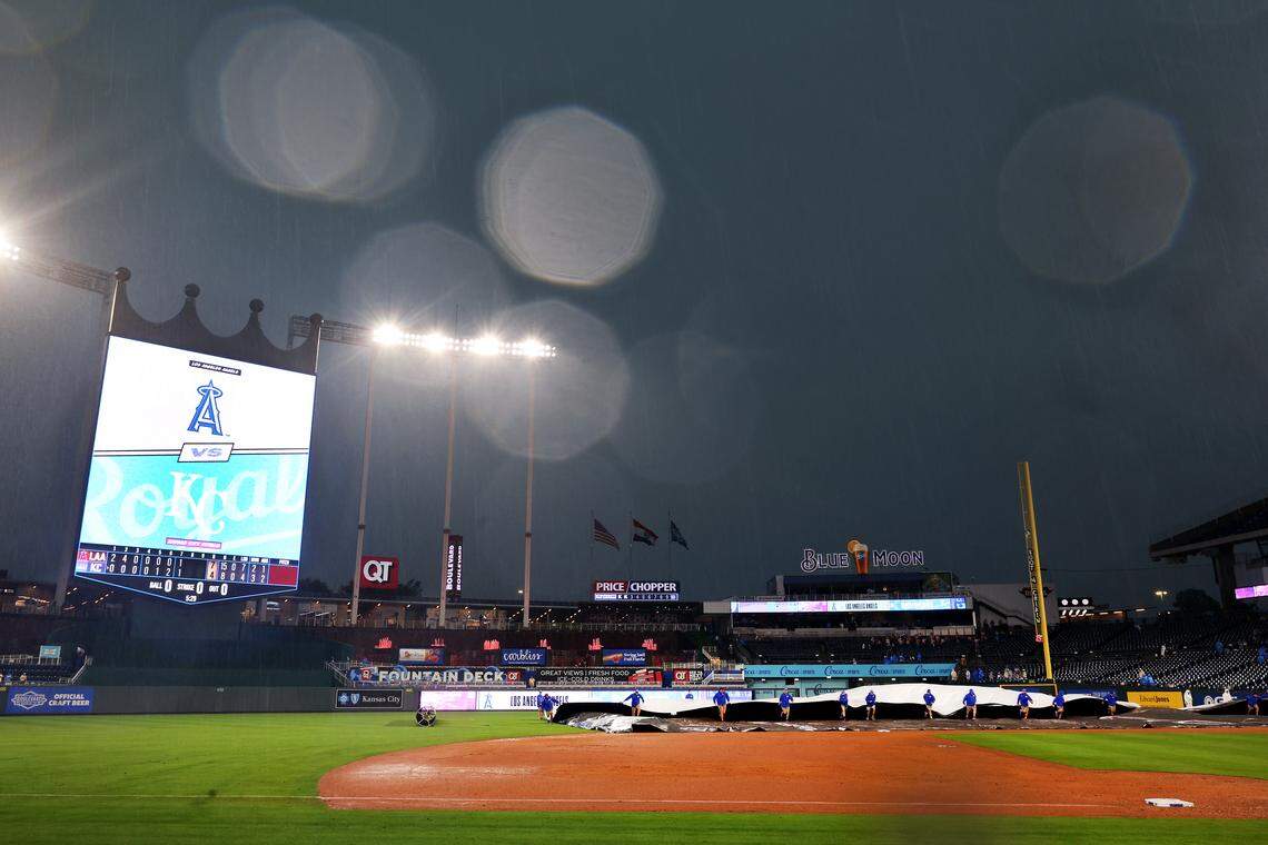 Kansas City Royals grounds crew members drag a tarp onto the field during a rain delay in the game against the Los Angeles Angels at Kauffman Stadium on April 26, 2026 in Kansas City, Missouri.