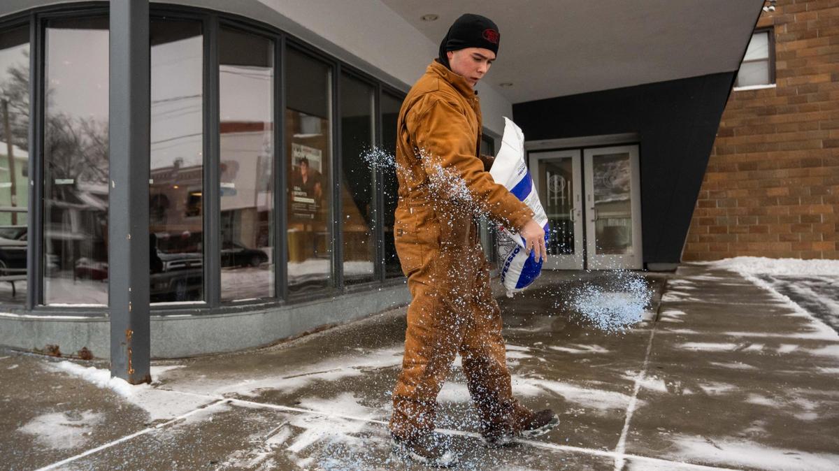 A young man named Nixom spreads ice melt in front of a Chipotle on 39th Street in Kansas City on Wednesday, Feb. 12. Kansas City was blanketed with snow overnight and into the early morning Wednesday.