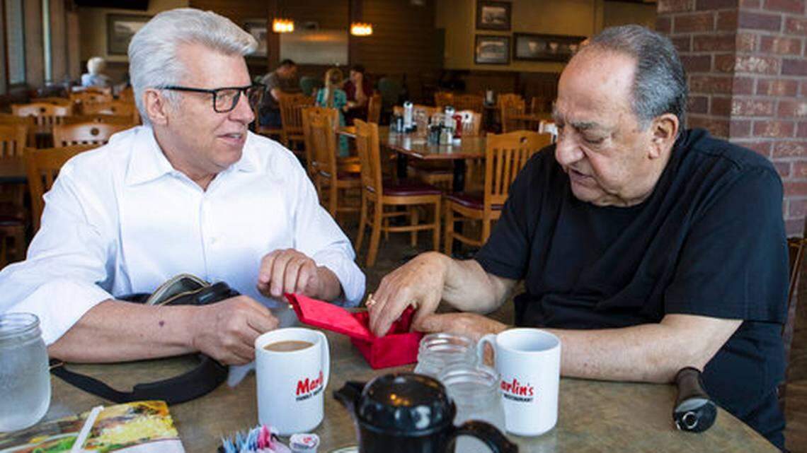 Gene Abdallah, former Minnehaha deputy sheriff, right, looks at his badge that was returned to him by the Rev. Duke Tufty of Kansas City during a surprise visit to Sioux Falls, S.D., on Thursday, May 17.