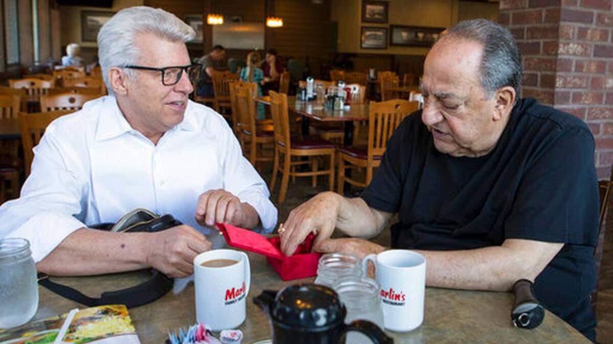 Gene Abdallah, former Minnehaha deputy sheriff, right, looks at his badge that was returned to him by the Rev. Duke Tufty of Kansas City during a surprise visit to Sioux Falls, S.D., on Thursday, May 17.