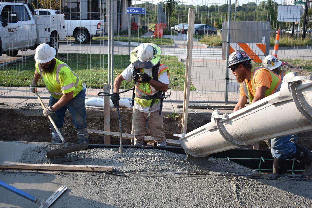 Construction workers pour cement around newly laid streetcar tracks in Berkley Riverfront Park on Wednesday. The project will eventually shut down a KC bridge for 30 to 60 days at a time.
