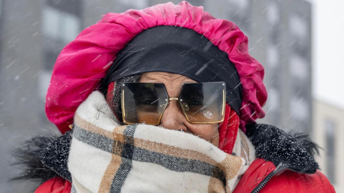 Brycandis Clardy, bundled up in a thick scarf and a bright red coat, stands for a portrait as heavy snow falls on Tuesday, Feb. 18, 2025, in Kansas City.