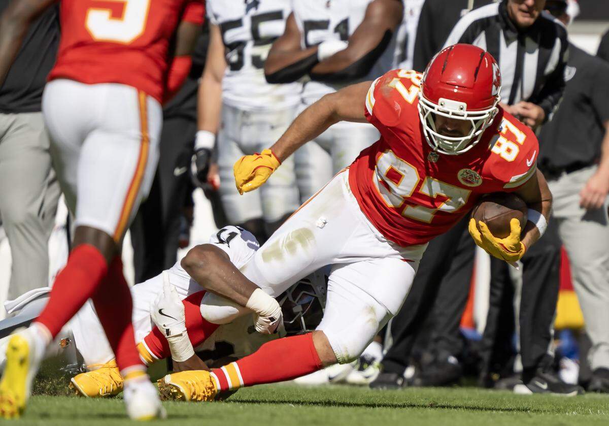 Kansas City Chiefs tight end Travis Kelce (87) carries the ball as he is tackled by Las Vegas Raiders safety Jeremy Chinn (11) during the second half on Sunday, October 19, 2025, at GEHA Field at Arrowhead Stadium in Kansas City. The Chiefs defeated the Raiders, 31-0.