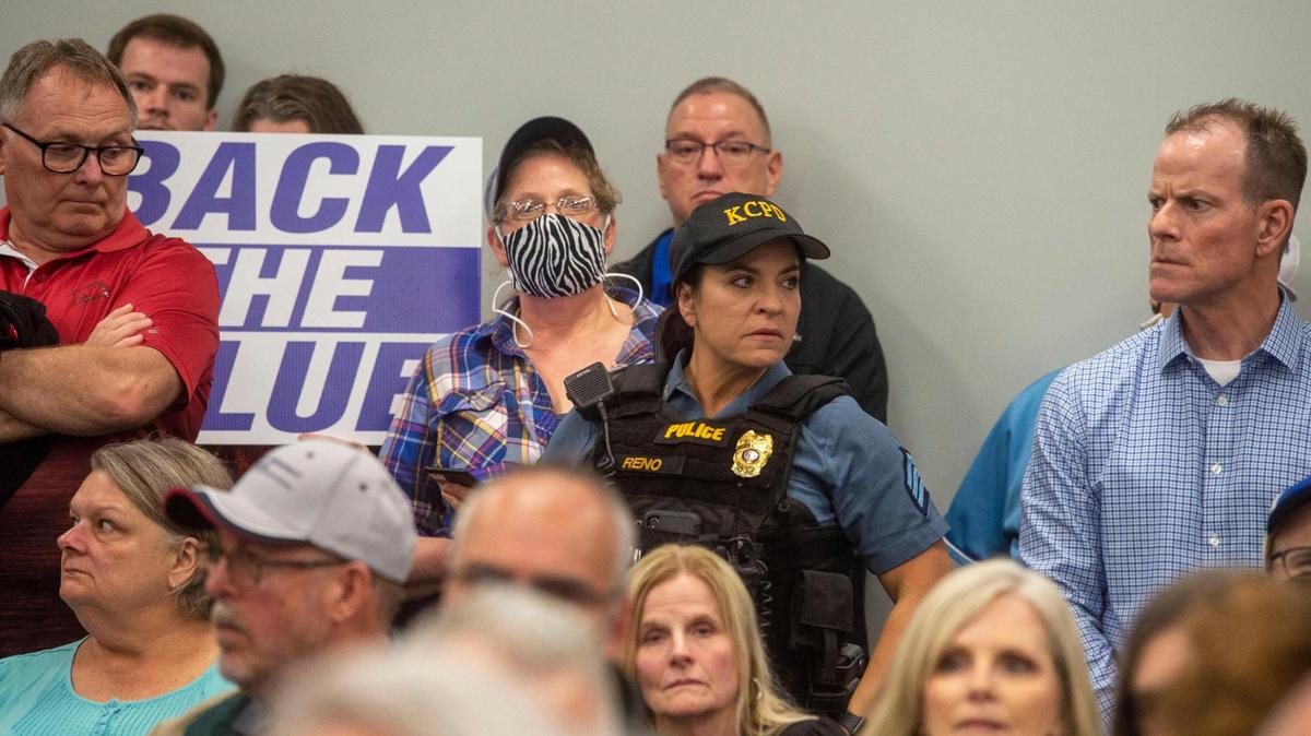A Kansas City police officer on duty stands among Northland residents waiting for the start of a town hall meeting last month. They came to express their concerns about the City Council’s plan to reassign funds from the police budget to other programs to help fight crime. The plan, championed by Mayor Quinton Lucas, was opposed by Northland council members.