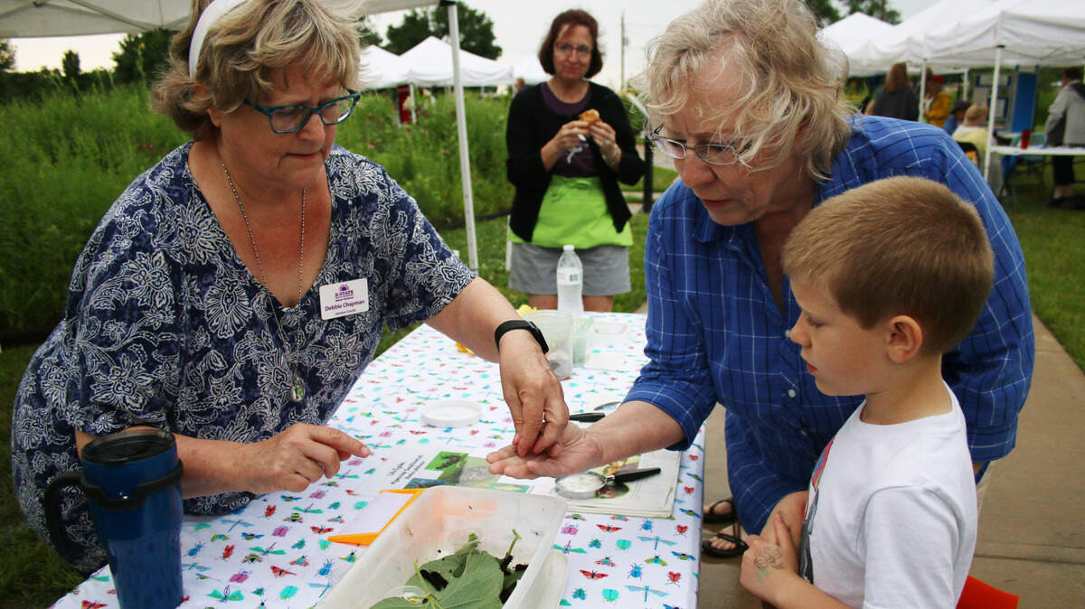 Debbie Chapman, a master gardener with Johnson County Extension, hands a caterpillar to Joyce Christopher and Max Wyly at the Wonders of Discovery event in 2019.