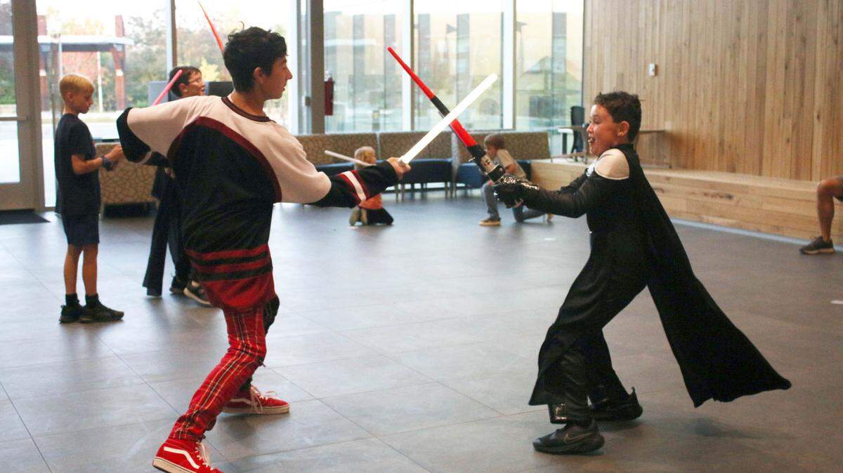 Olathe residents Parker Kabler, 13, and Ace Stuart, 7, have a lightsaber battle at Indian Creek Library during the Star Wars night program.