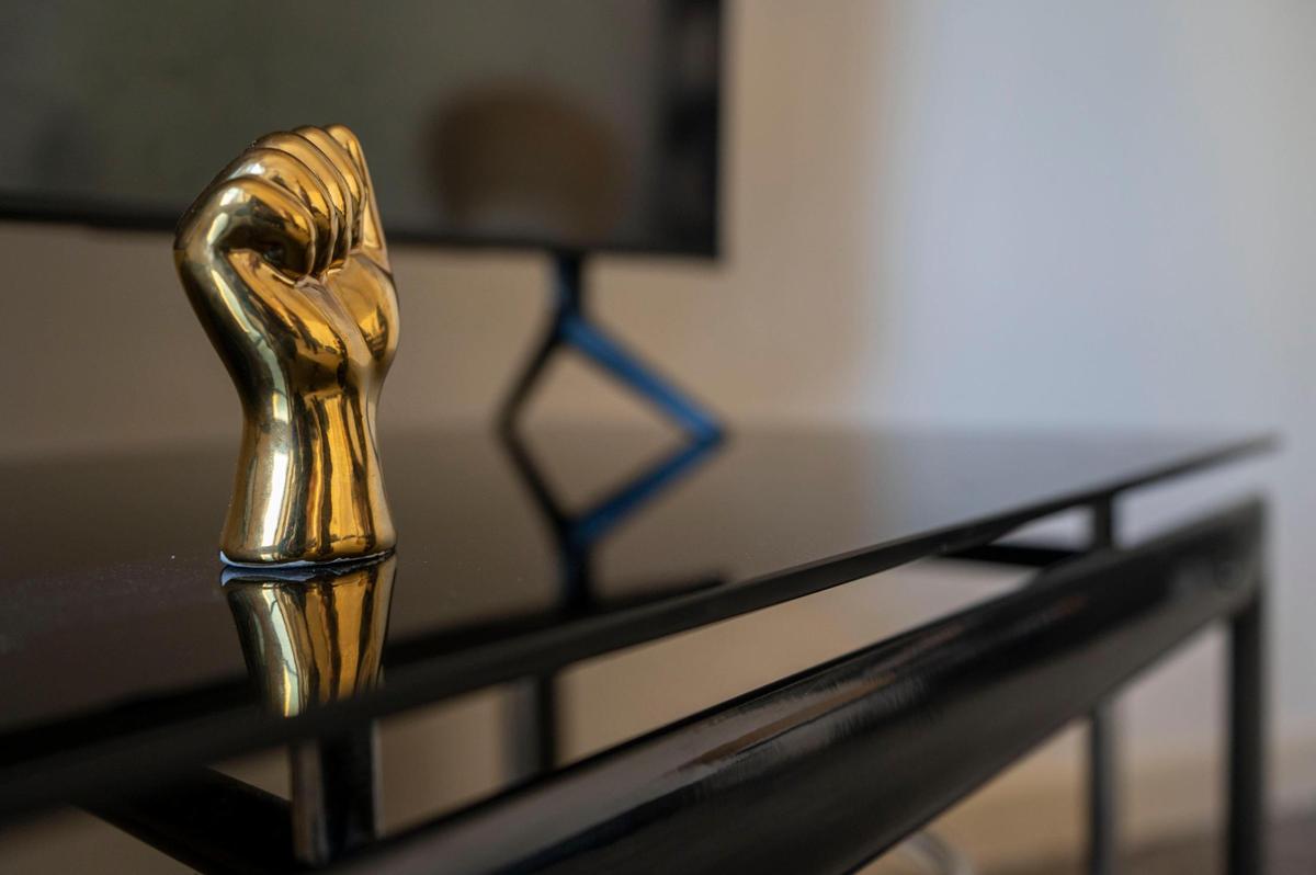 Justin Layton displays a gold fist on his television stand while speaking about his experience with the Independence Police Department at his home in Kansas City on Tuesday, March 15, 2022. Layton claims the police violated his civil rights when they arrested him just over two years ago for “jaywalking.”
