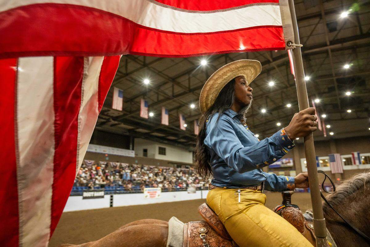 Erica Singleton parades around the American flag prior to the start of the Black Rodeo USA show at Hale Arena in Kansas City on Saturday, July 26, 2025. Before every show, Singleton walks the American flag out for the national anthem.