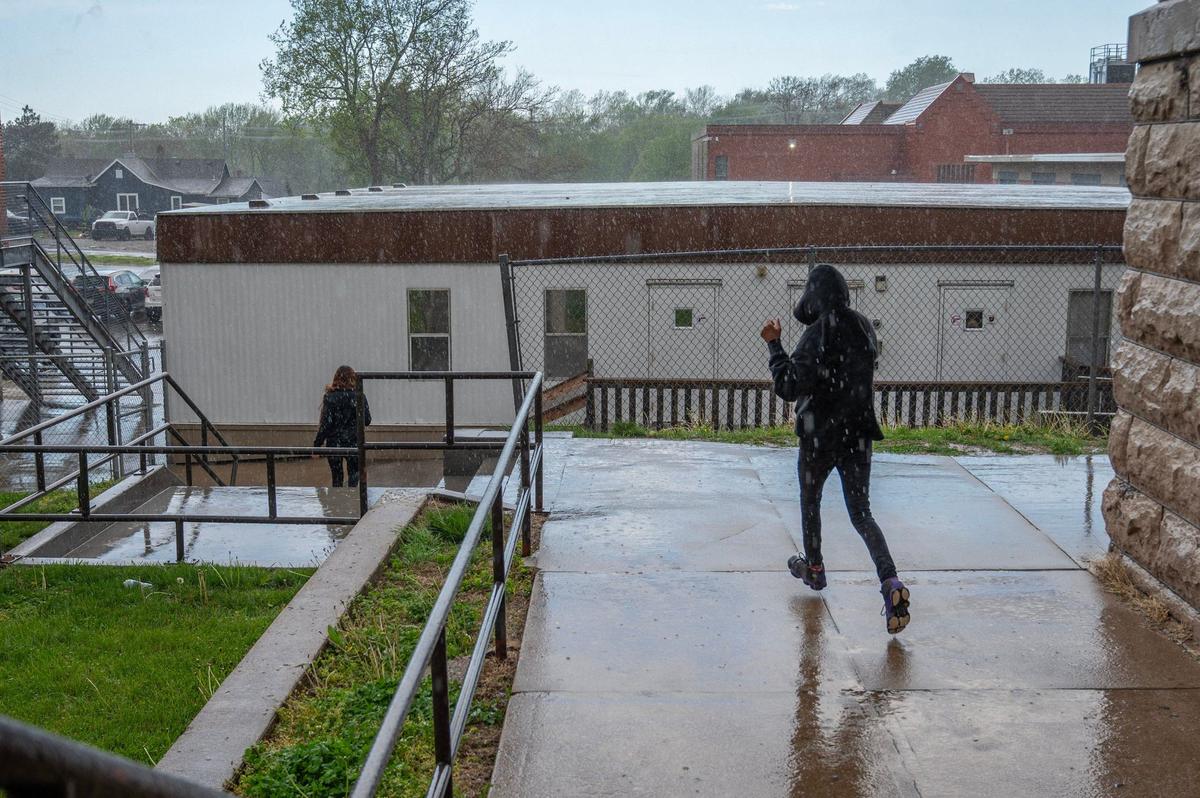 Students walk in the rain to get to the mobile classrooms at Central Middle School on Tuesday, April 16, 2024, in Kansas City, Kansas.