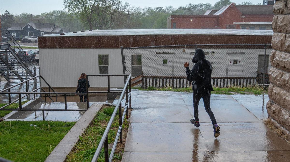 Students walk in the rain to get to the mobile classrooms at Central Middle School on Tuesday, April 16, 2024, in Kansas City, Kansas.