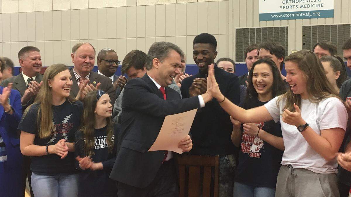 Gov. Jeff Colyer high-fived students at Seaman High School in Topeka before signing a bill intended to boost school funding by more than $500 million over five years.