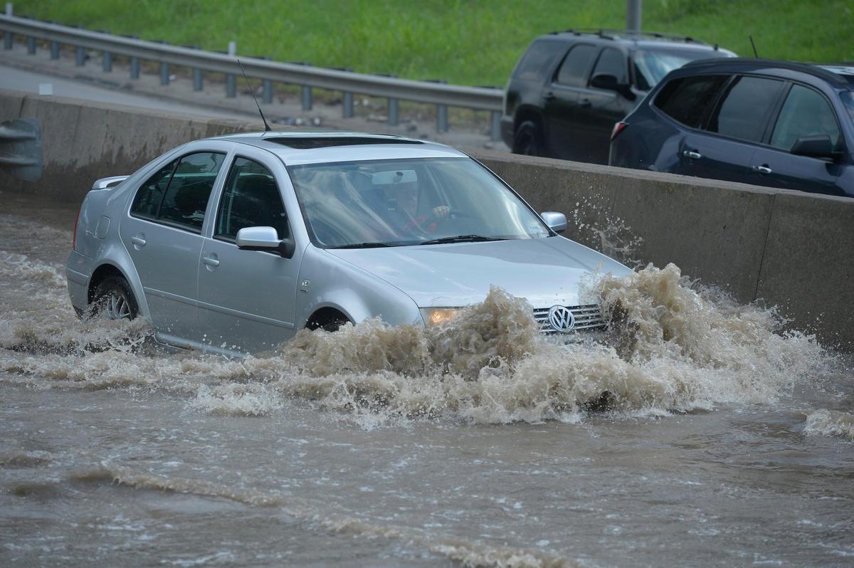 Cars splash through floodwater on the Southwest Trafficway on ramp to northbound Interstate 35 heading toward downtown Kansas City, Wednesday after heavy rains flooded the area. The interstate was impassible for a while due to water pooling in the lanes.