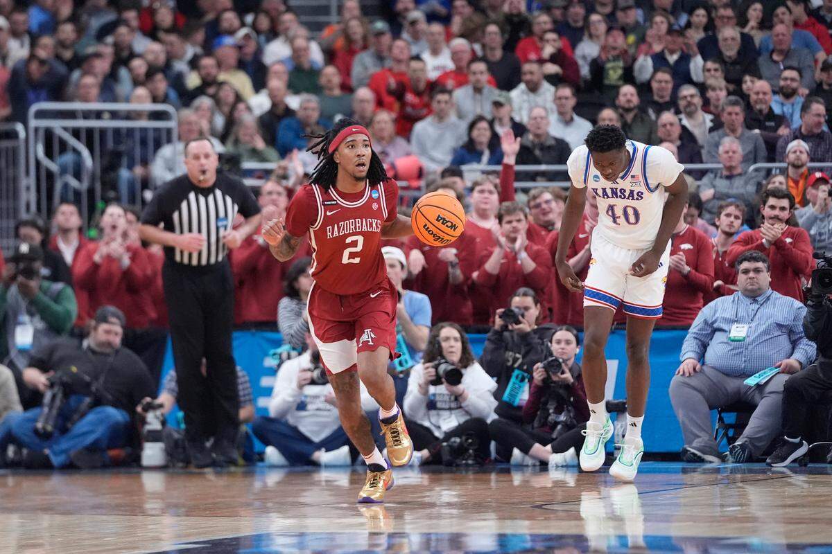 Arkansas Razorbacks guard Boogie Fland, left, brings the ball up the court against the Kansas Jayhawks during a first-round NCAA Tournament men’s basketball game at Amica Mutual Pavilion in Providence, Rhode Island, on Thursday, March 20, 2025.