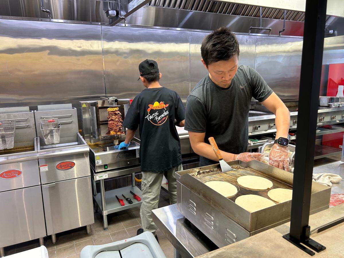 Derrick Lam cooks hand-cranked tortillas for a customer.