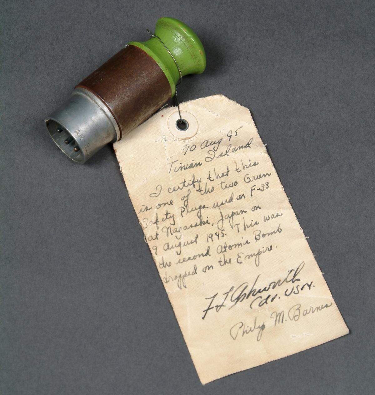 This is a plug that was removed from the atomic bomb named Fat Man to arm it moments before being detonated over Nagasaki, Japan. The plug was donated to the Harrys S. Truman Presidential Library and Museum by Philip Barnes, an electronic test officer on the flight who kept the safety plugs after they were pulled from the bomb and replaced with the red arming plugs. The note that came attached to the plug is signed by Barnes and Navy Commander Frederick Ashworth, the weaponeer responsible for arming the bomb is to authenticate the provenance of the artifact.