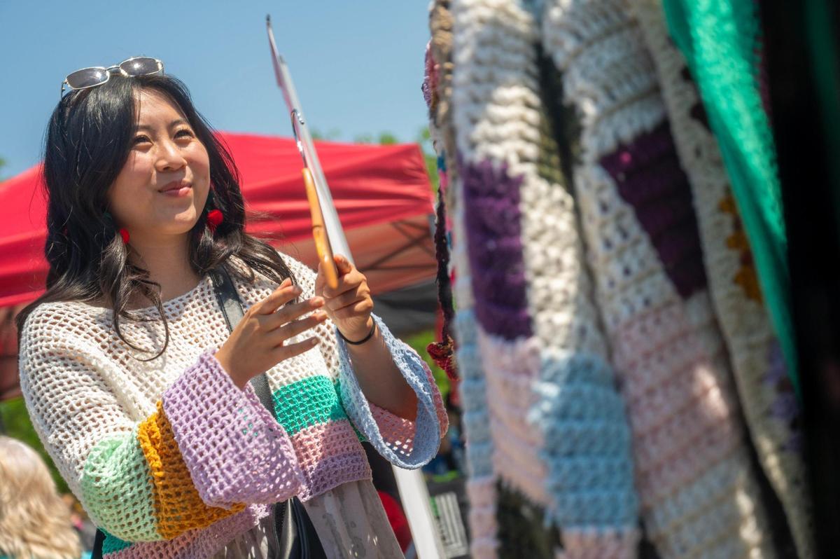 Trisha Xue organizes a rack of clothing at the Cool Aunt Trish booth during the AAPIconic Festival on Saturday, May 20, 2023, in Kansas City.