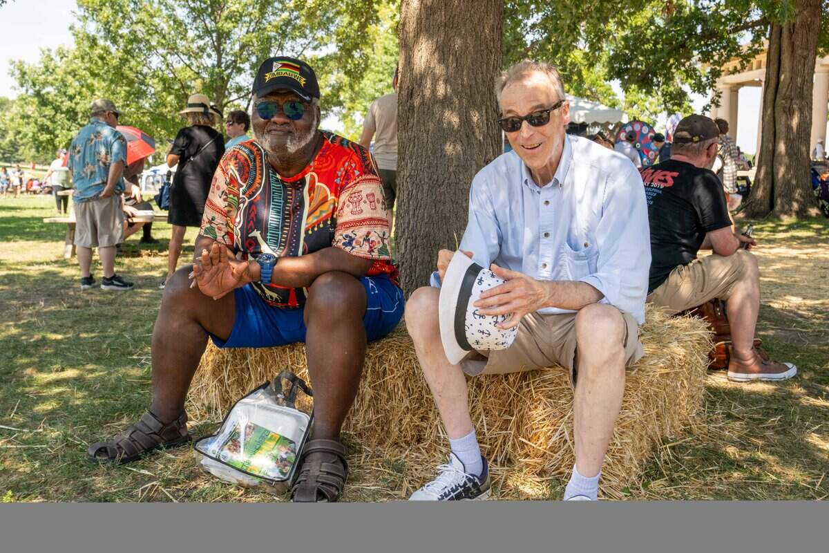 Matthew Hamilton and Reed Oltvedt sit in the shade at the Ethnic Enrichment Festival in Swope Park on Saturday, Aug. 16, 2025, in Kansas City. The annual festival celebrates the many different cultures and ethnicities that exist in Kansas City, with vendor booths, cultural education opportunities, and performances. This year, the festival goers braved nearly 100 degree heat.