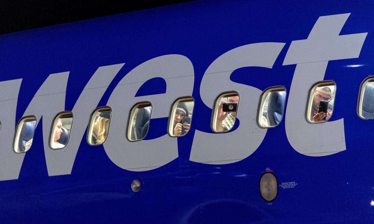 Passengers aboard Southwest Airlines flight 3369 peer out from the windows of a Boeing 737-700 airliner before it took off as the final flight from Kansas City International Airport’s old terminals on Monday, Feb. 27, 2023, in Kansas City.