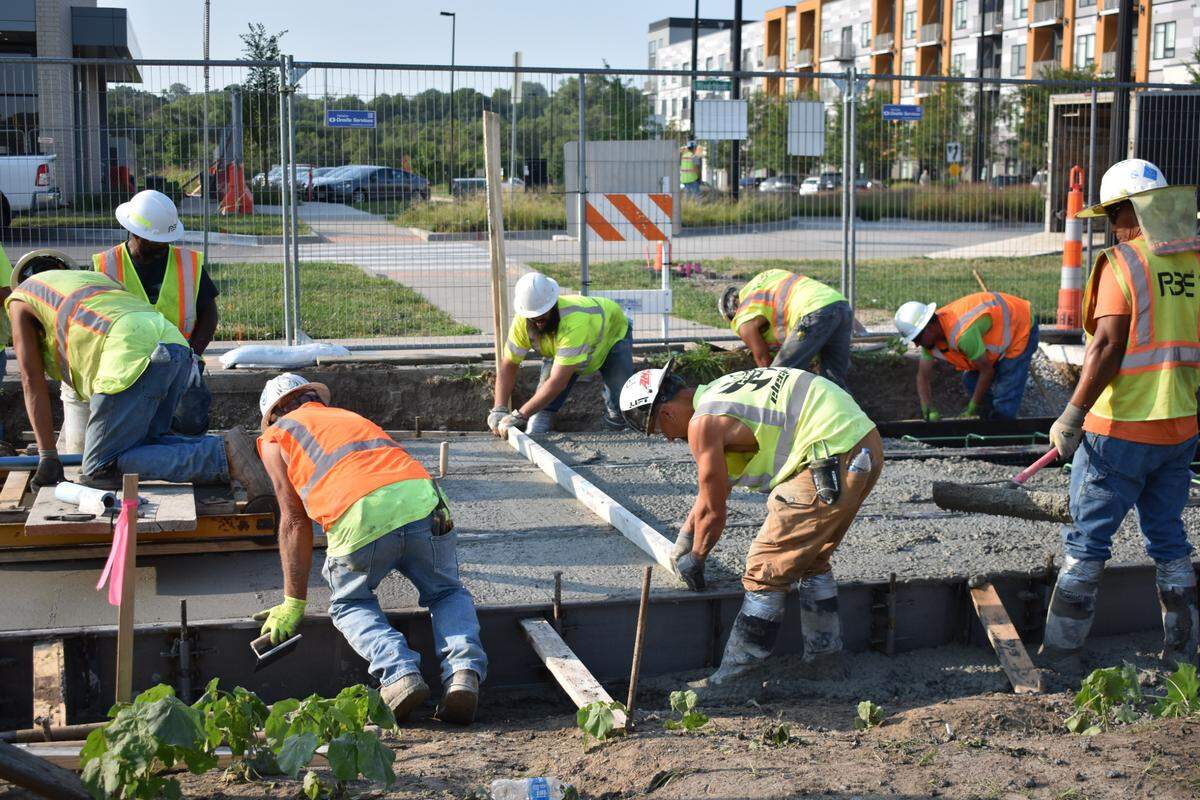 Construction workers smooth cement around newly laid streetcar tracks in Berkley Riverfront Park. The project is intended to boost development and traffic to the area.