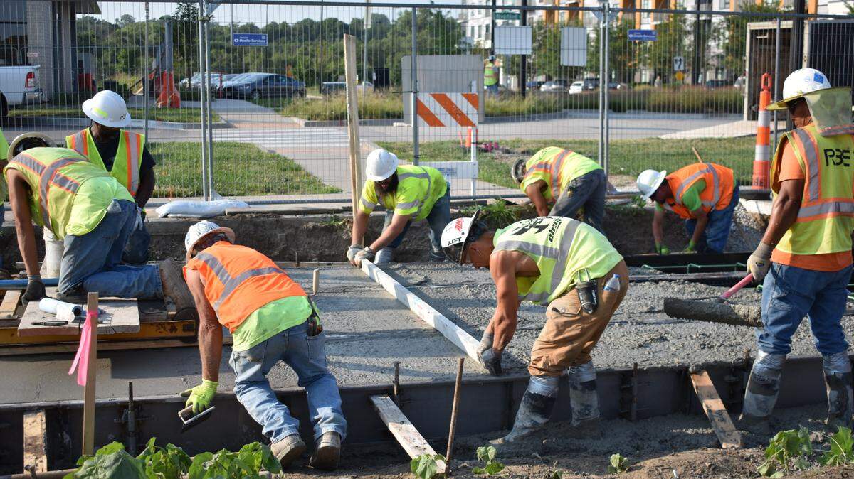 Construction workers smooth cement around newly laid streetcar tracks in Berkley Riverfront Park on Wednesday, July 10, 2024. The track slab is the first to be poured for the streetcar’s 0.7-mile riverfront extension.