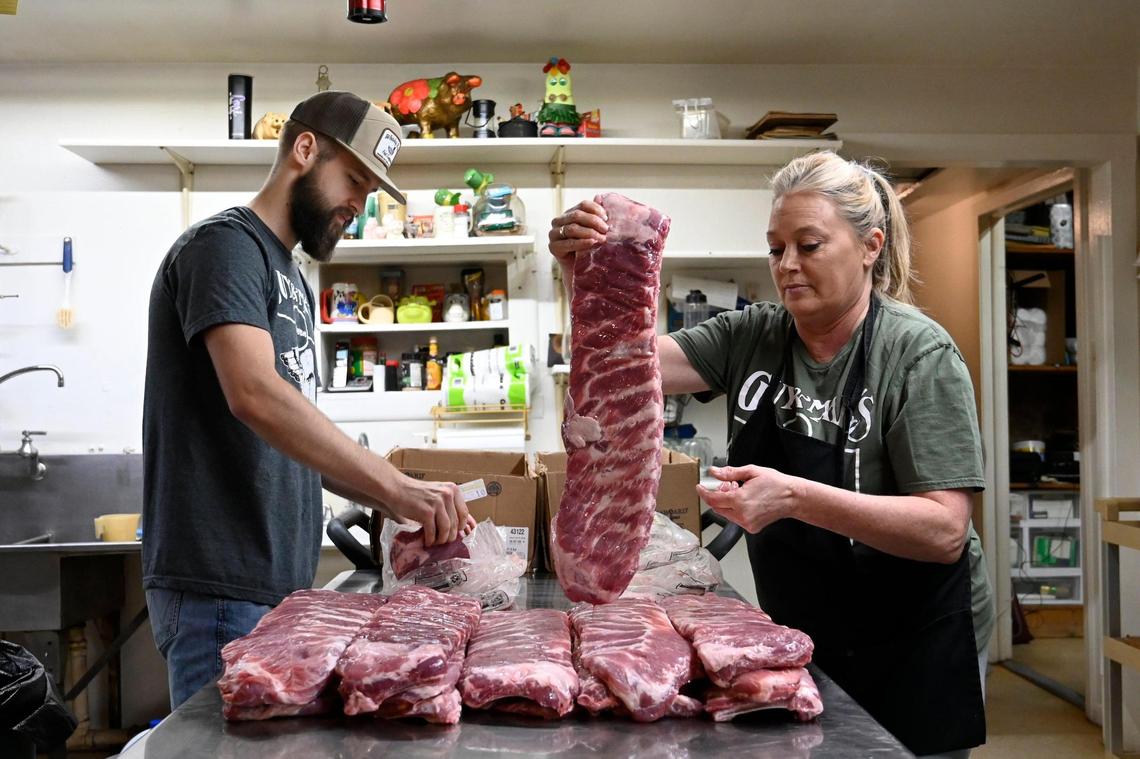Wyatt Thompson, left, and Tammy Harabin ready 72 slabs of ribs to be trimmed and seasoned before going into the smoker.