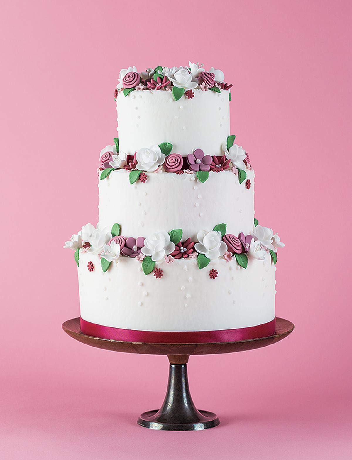 GARDEN DELIGHT Handcrafted blooms bring the garden to life in this three-tier cake from Sugar &amp; Spice Catering. Wood and pewter cake stand available to rent from Ultrapom.