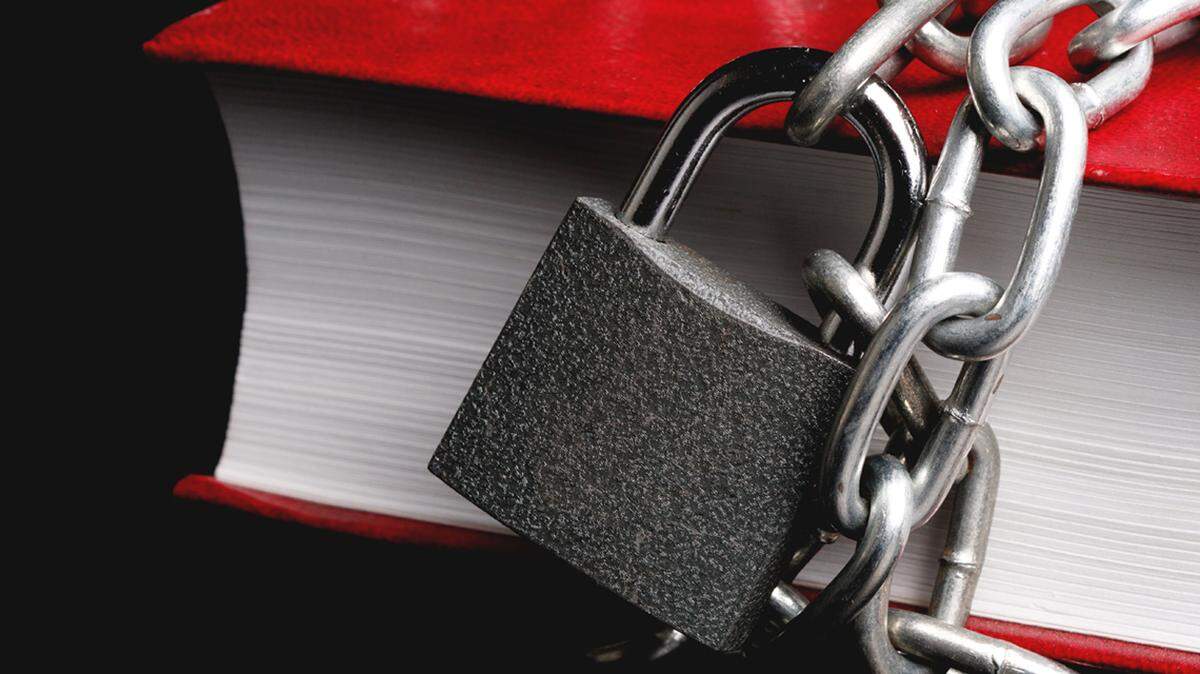 part of the red book which has a chain connected to the chain hanging lock, a metal chain with a glare book ban banned library libraries censorship censor remove