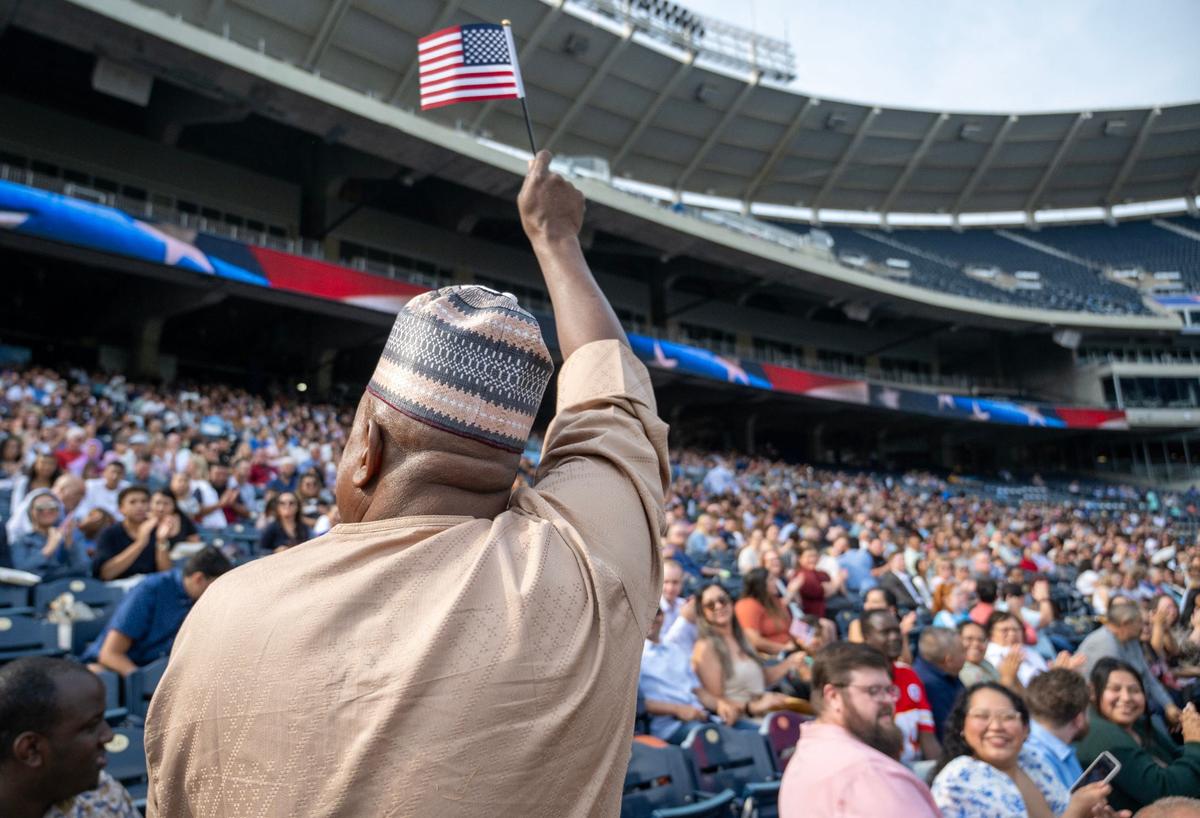 Abubakar Karaye, waves the American flag as his native country of Nigeria is recognized during a naturalization ceremony at Kauffman Stadium in Kansas City on Thursday, Sept. 12, 2024.