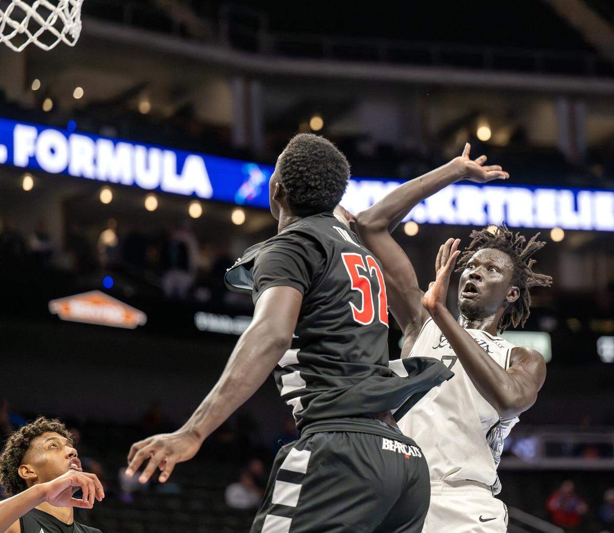 UCF Knights center John Bol (7) watches the ball as he makes a layup over Cincinnati Bearcats center Moustapha Thiam (52) during the second half of a Big 12 Men's Basketball Tournament game at T-Mobile Center on Wednesday, March 11, 2026, in Kansas City.