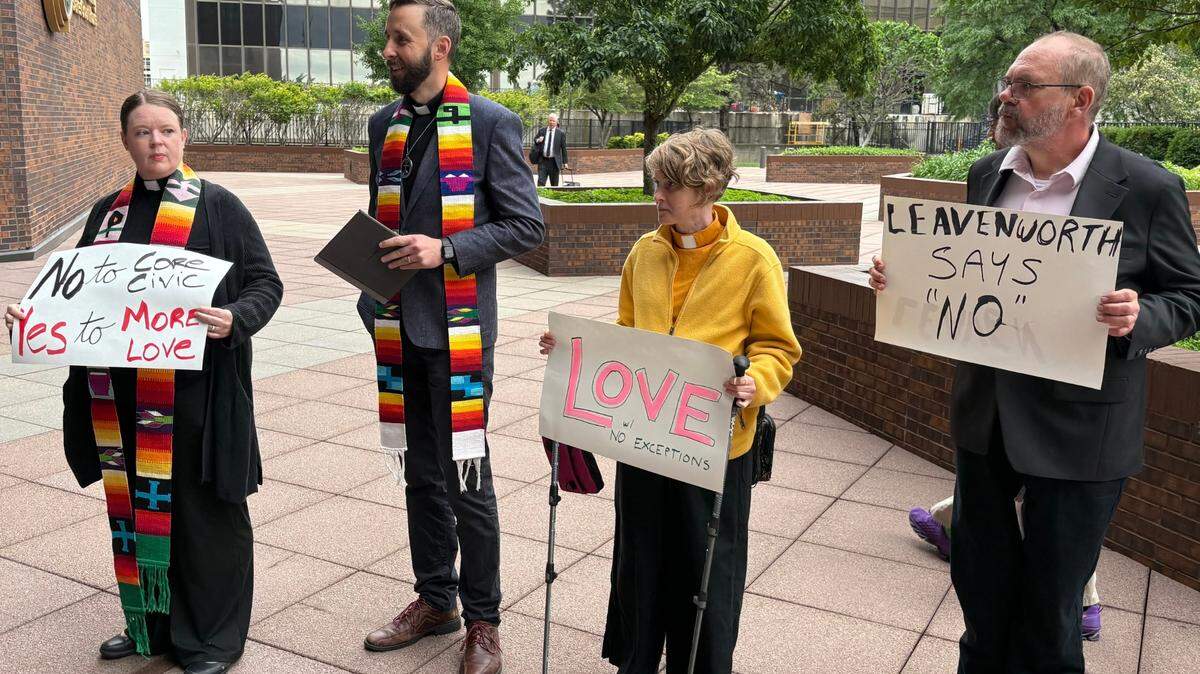 Protesters hold signs denouncing CoreCivic outside a Topeka courthouse on May 20, 2025.