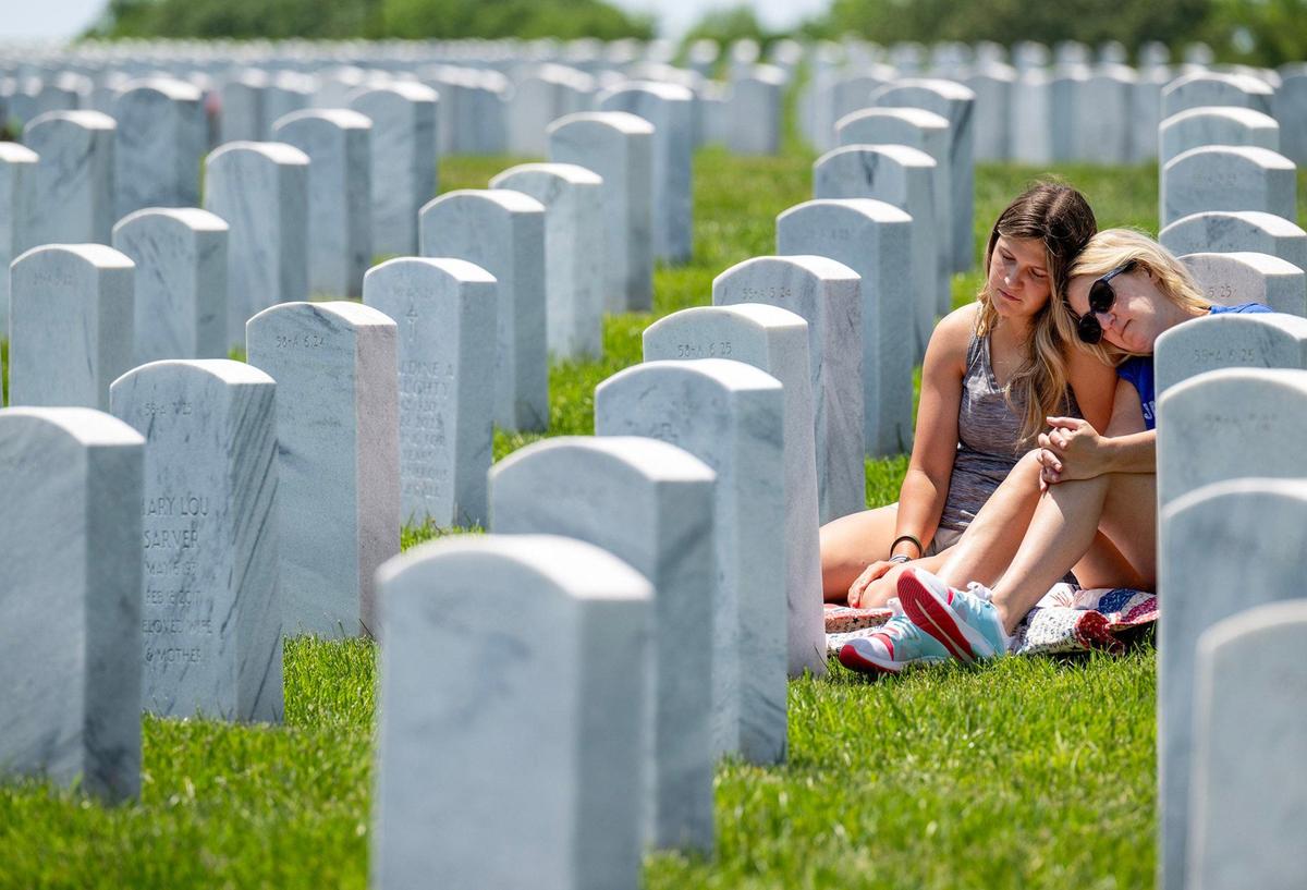 Crosby Taylor, left, and her mother, Sarah Taylor, of Shawnee, take time to reflect and pay tribute to William R. Jones, Crosby’s grandfather and Sarah’s father, during a visit to his grave at Leavenworth National Cemetery on Thursday, May 23, 2024, ahead of the Memorial Day holiday. Jones, a Navy veteran, passed away in 2013.