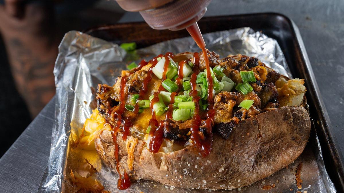 Thomas Clark, owner of TCs Fully Loaded food truck, topped one of his signature KC loaded baked potatoes with barbecue sauce. The hefty, one-pound-plus potato was loaded with burnt ends, cheddar cheese, green onions, and served with a side of sour cream.
