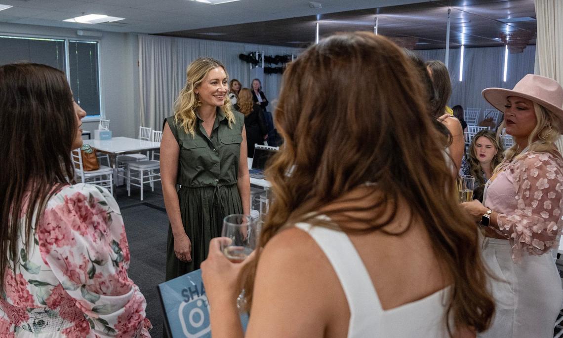 Martine Harris, co-owner of Essense of Australia, speaks to attendees after the bridal dress fashion show at True Society on Monday, Aug. 5, 2024, in Lenexa.