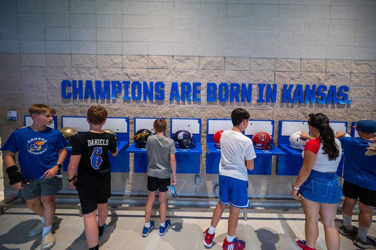A group of kids look at high school football championship team helmets in a section located inside the newly remodeled David Booth Kansas Memorial Stadium during the Jayhawks game vs. the Fresno State Bulldogs on Saturday, Aug. 23, 2025, in Lawrence.