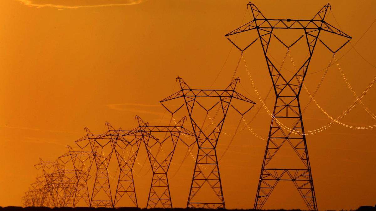 High voltage electric transmission lines are silhouetted against the late day sky near Spearville, Kan.